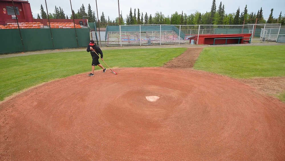 Photo by Rashah McChesney/Peninsula Clarion  Kyle Richardson, head coach of the Peninsula Oilers baseball team, fixes home plate before the team's season opener Saturday June 7, 2014 in Kenai, Alaska.