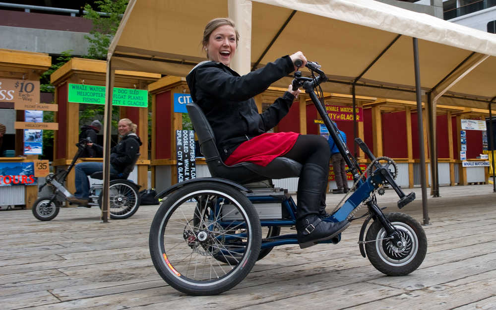 ADVANCE FOR WEEKEND EDITIONS JUNE 7-8 - In this May 30, 2014 photo, Kellen Priest, right, and Abby Leatherman, both tour brokers for Gastineau Guiding, ride electric-powered tricycles downtown in Juneau, Alaska. in Juneau, Alaska. Bob Janes invented the Access Hybrid, a trike with an assistive electric motor, meant to provide all the fun of a bicycle and all the function of a traditional mobility device. (AP Photo/The Juneau Empire, Michael Penn)