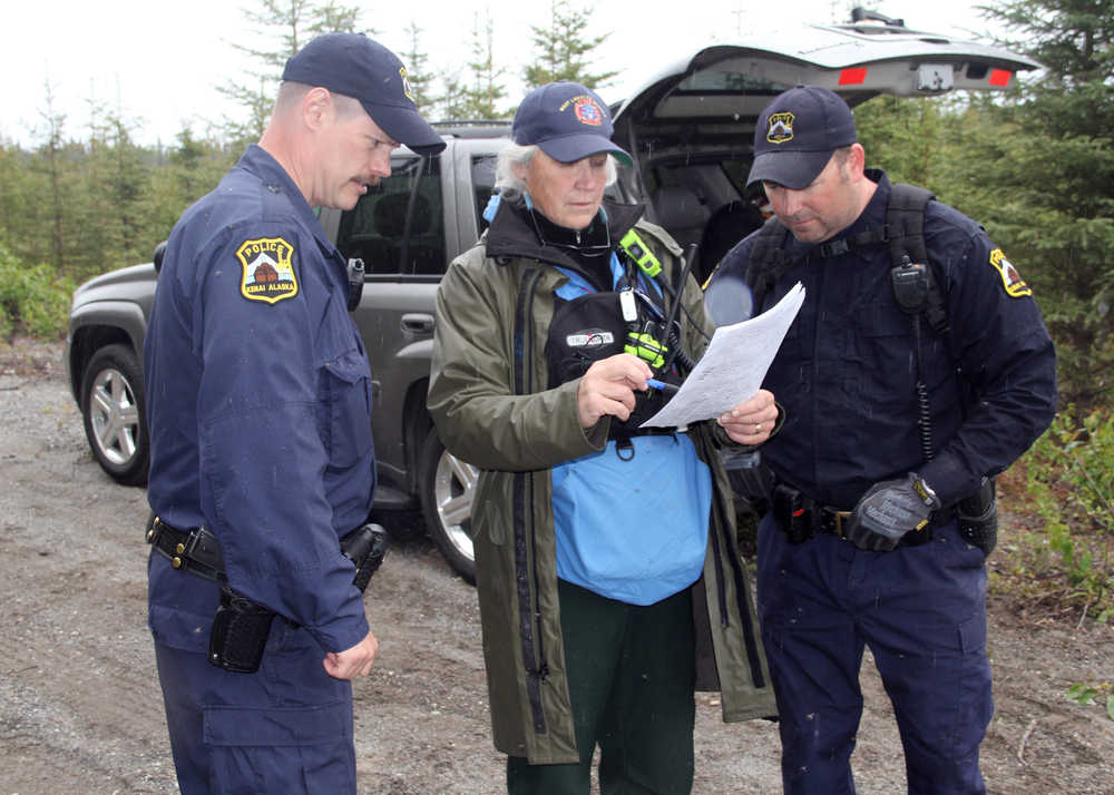 Photo by Dan Balmer/Peninsula Clarion Kenai Police Sgts. Scott McBride (left) and Jay Sjogren review a map with Lisa Jaegar from the Mat-Su Search and Rescue Dogs on Borgen Av. Monday in North Kenai. Two rescue dog teams along with agents with the FBI are searching the wooded area north of Wildwood Correctional Facility for a Kenai family of four missing since May 27.