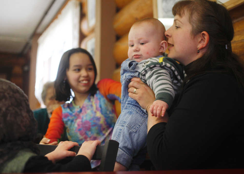 Photo by Rashah McChesney/Peninsula Clarion  Louise Coffey whispers to her son Aldric Coffey during a gathering at Fort Kenay after a blessing ceremony at the Holy Assumption of the Virgin Mary Russian Orthodox church's new outbuilding Thursday June 12, 2014 in Kenai, Alaska.