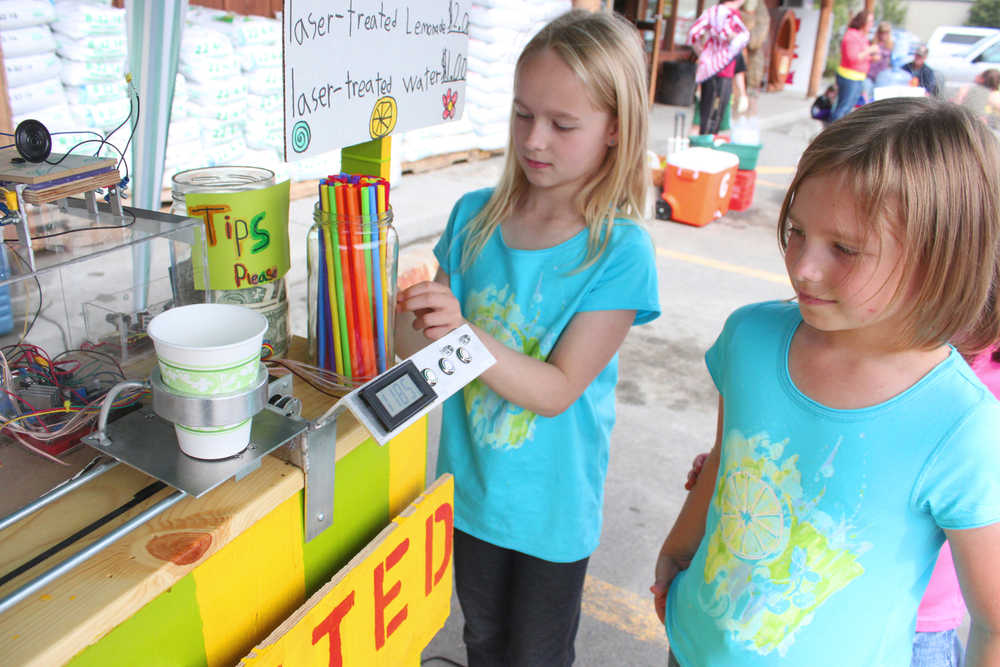 Photo by Kelly Sullivan/ Peninsula Clarion Emily Moss and Masidon McDonald watch their robotic lemonade stand treat their lemonade with laser beams, Saturday, June 14, in Soldotna.
