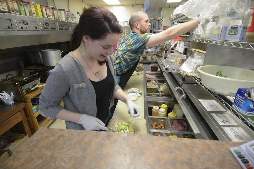 Photo by Rashah McChesney/Peninsula Clarion  Megan Schaafsma makes a sandwich as Ruari Tuite works alongside her at Odie's Deli Wednesday June 18, 2014 in Soldotna, Alaska. Schaafsma is buying the business from longtime owner Melodie Symington who first opened the deli in 2005. Schaafsma will take over both the Kenai Airport and Soldotna locations.