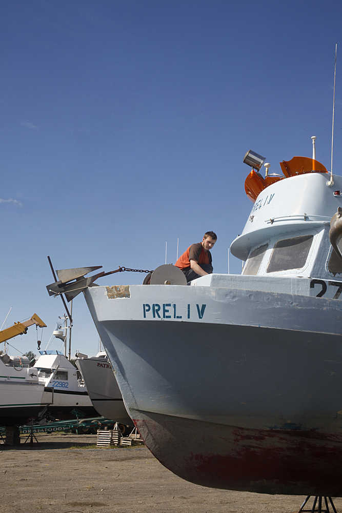 Photo by Rashah McChesney/Peninsula Clarion A "Fish or Cut Bait" flag flies in the wind on a boat sitting on blocks at the Snug Harbor Seafoods receiving dock Thursday June 19, 2014 in Kenai, Alaska.