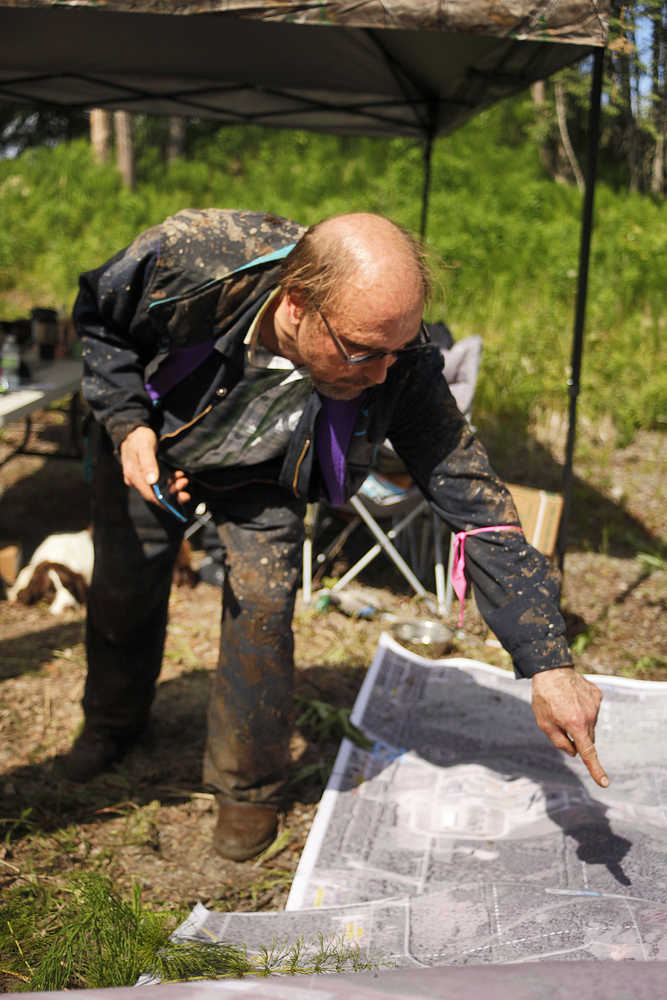 Photo by Rashah McChesney/Peninsula Clarion Matt Schilf, of Kenai, points to a spot on a large map of a portion of Kenai near the home of a missing Kenai family Tuesday June 24, 2014 in Kenai, Alaska.  Schilf and 14 others spent the bulk of the day searching in the woods for signs of the family.