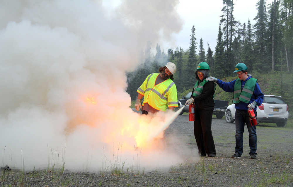 From left: Community Emergency Response Teams instructor Michael Huckabay coaches CERT students Delayna Baczkowski and Jackson Blackwell how to put out a small fire using the PASS method - pull, aim, squeeze and sweep - on Wednesday at the Central Emergency Services Station 2 on Mackey Lake Road. CERT classes started this week and run through July 12. Photo by Kaylee Osowski/Peninsula Clarion
