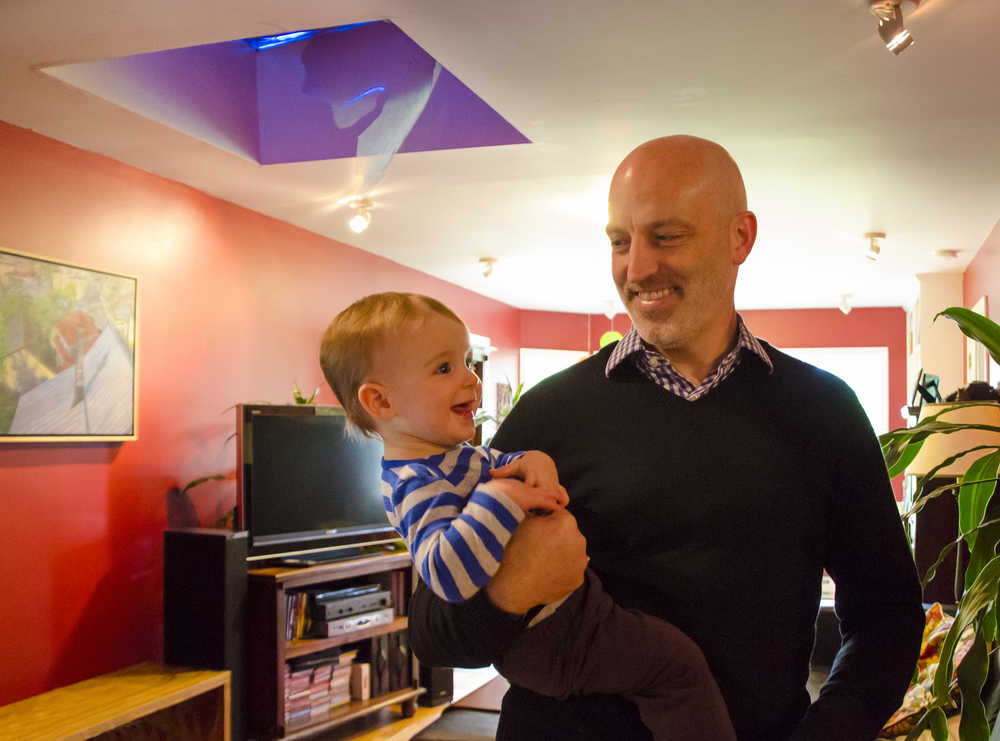 Glenn Merrill, 45, holds Jackson Merrill in front of their broken skylight in their living room on Tuesday. A black bear climbed up on their roof and crashed through the skylight on Saturday minutes before Jackson's first birthday party.