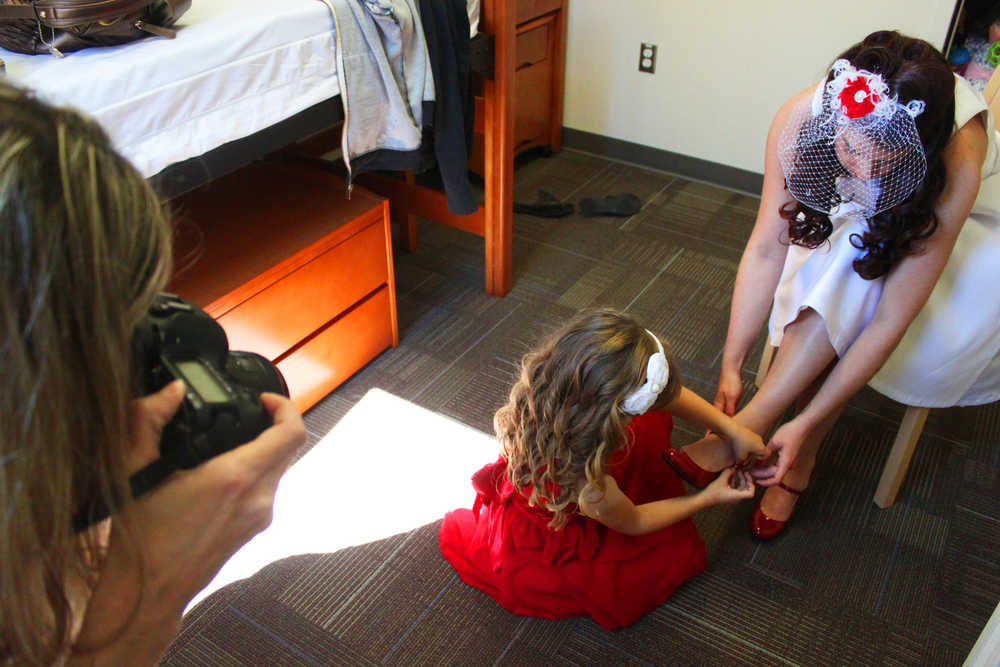 Photo by Kelly Sullivan/ Peninsula Clarion Jamie Moorhead, photographer for Kristin Siter's wedding, takes pictures of Siter's daughter Angel Sisneros helping strap her mother's on high heels, Saturday, June 28, at the Kenai Peninsula College Residence Hall.