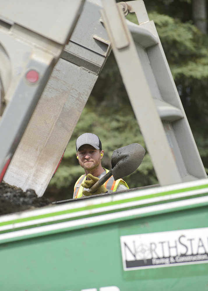 Photo by Rashah McChesney/Peninsula Clarion Cody Slemp uses a shovel to keep a pre-asphalt leveling material pouring out of a dump truck as a NorthStar Paving and Construction crew works on a new portion of a bicycle trail running along Kalifornsky Beach Road Thursday July 3, 2014 in Kenai, Alaska.