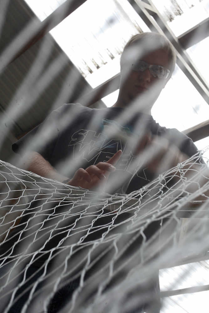 Photo by Rashah McChesney/Peninsula Clarion Dawson Herrick, 19, weaves line onto a dipnet at Mike's Welding Wednesday July 9, in Sterling, Alaska.