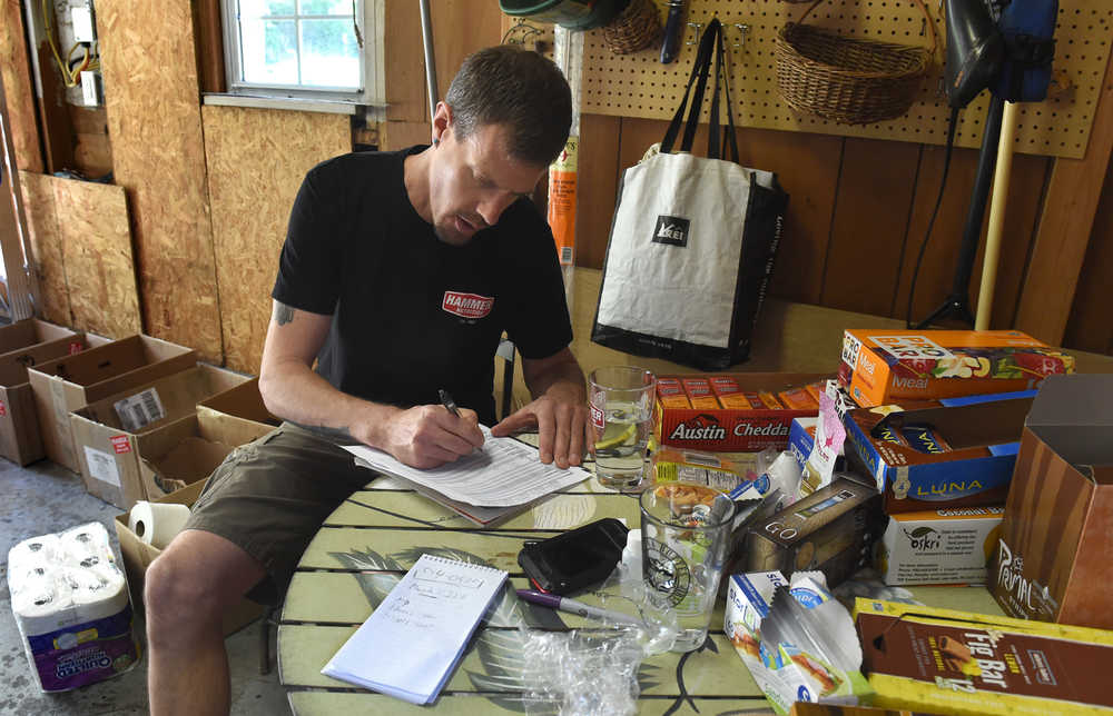 This June 9, 2014 photo shows extreme hiker/biker Adam Bradley checking off items on his resupply list for a 16,000-mile trip that will start at his back door in Reno in July. It is a half and half cycling and walking trip. (AP Photo/Reno Gazette-Journal, Andy Barron)