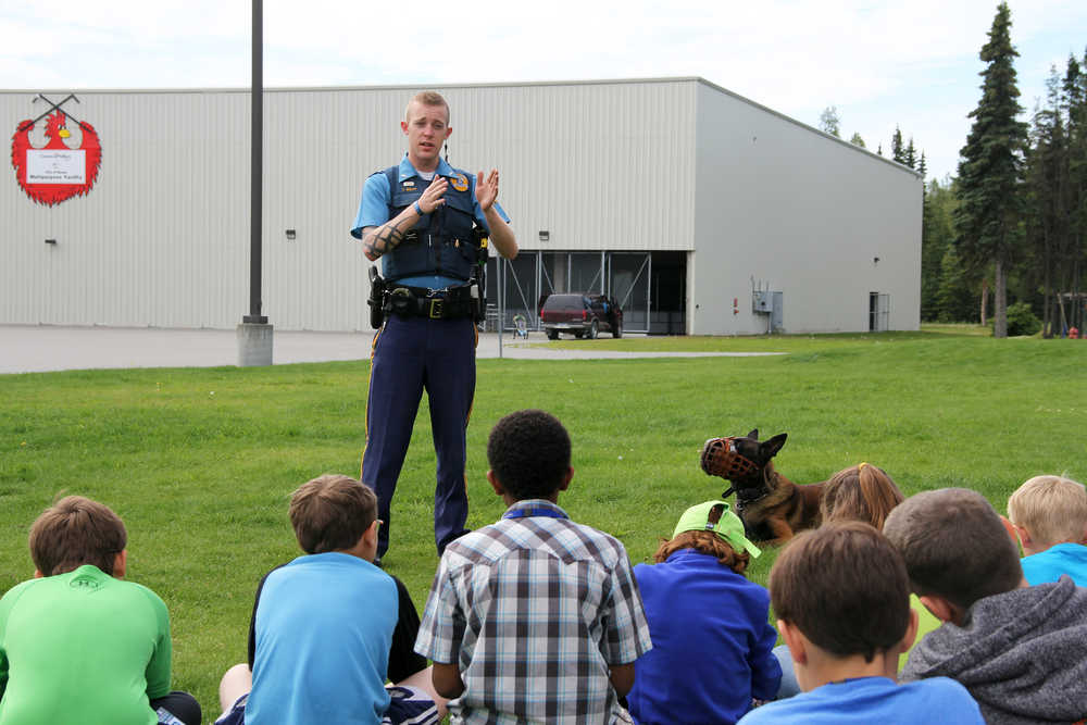 Photo by Dan Balmer/Peninsula Clarion Tim Wolff with the Alaska State Trooper K-9 Unit answers questions from students of the Crime Scene Investigators moonbase camp Tuesday at the Challenger Learning Center in Kenai. Wolff explained how his dog Scout helps find suspects during investigations. The CSI moonbase camp teaches forensics skills that 28 students will apply in a mock investigation. The camp started Sunday and ends Friday.