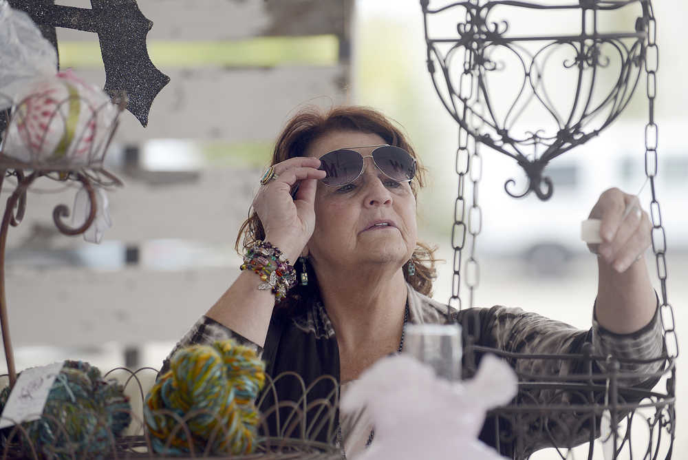 Photo by Rashah McChesney/Peninsula Clarion  Margo Bouchard checks the price of a hanging basket at the new Swank Street Antiques & Art Market Saturday July 19, 2014 in Soldotna, Alaska.