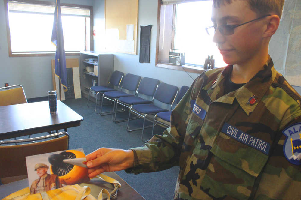 Photo by Kelly Sullivan/ Peninsula Clarion Kenai Civil Air Patrol Cadet Bradley Walters holds the photograph of the owner of the maintained World War II Advanced Trainer he flew in Saturday, at the Civil Air Patrol hanger.