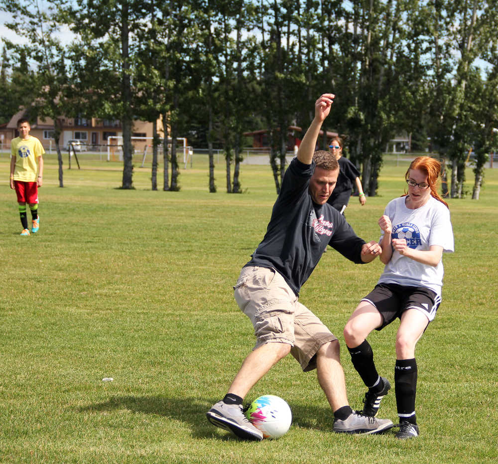 Photo by Dan Balmer/Peninsula Clarion Jake Wilkinson, 26, of Kenai tries to get past his niece Hailey Wilkinson, 14 in a friendly soccer match Sunday at the Kenai Middle School field. Kids from the Boys and Girls Club took on adults in the soccer game.
