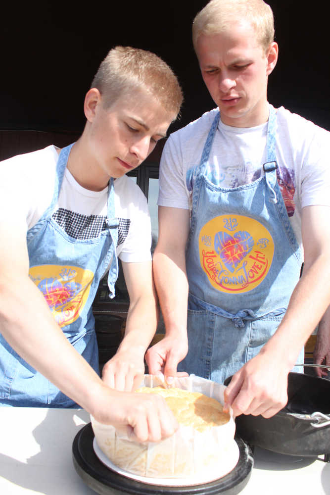 Photo by Kelly Sullivan/ Peninsula Clarion Jonas Vikstrom and Sebastian Gabriel remove their apple cake from a Dutch oven, Saturday, July 19, in Soldotna.