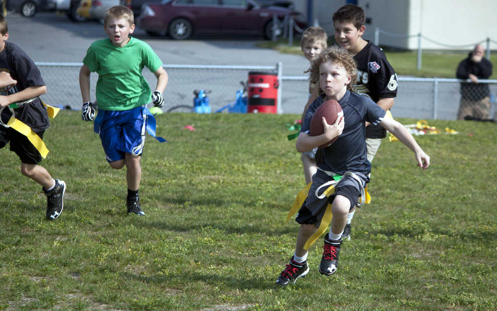 Photo by Dan Balmer/Peninsula Clarion Reagan Graves,9, carries the ball while Noah Harper, 10 attempts to pull his flag during a football scrimmage Monday at Soldotna High School. Nearly 50 kids participated in the Kenai Peninsula Youth Football Camp, led by Soldotna High football coach Galen Brantley. The camp, open to kids through eighth grade, runs through Wednesday.