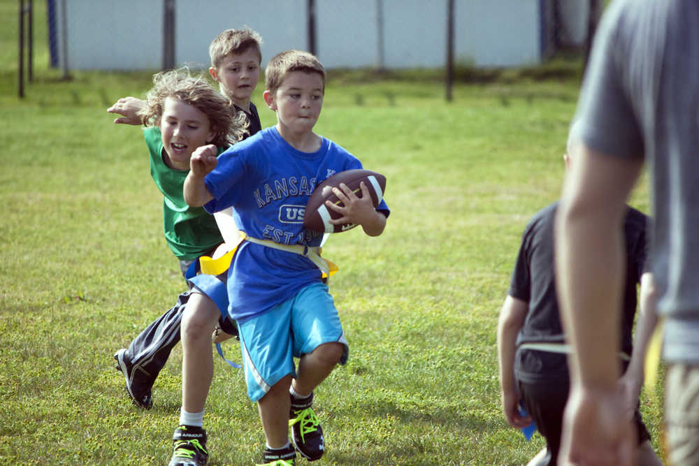 Photo by Dan Balmer/Peninsula Clarion Adam Harper, 8, carries the ball upfield during a football scrimmage Monday at Soldotna High School. Harper, known as "Beast Mode" on the field, was one of nearly 50 participants at the Kenai Peninsula Youth Football Camp, led by Soldotna High football coach Galen Brantley. The camp, open to kids through eighth grade, runs through Wednesday.