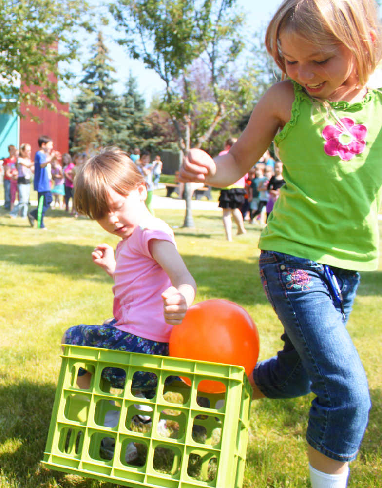 Photo by Kelly Sullivan/ Peninsula Clarion Shelby Hatfield, 8,  and Lydia Schwartz, 7, finish a balloon race where they could not use their hands to transport it across the field, Tuesday, July 22, at the Joyce K. Carver Soldotna Public Library.