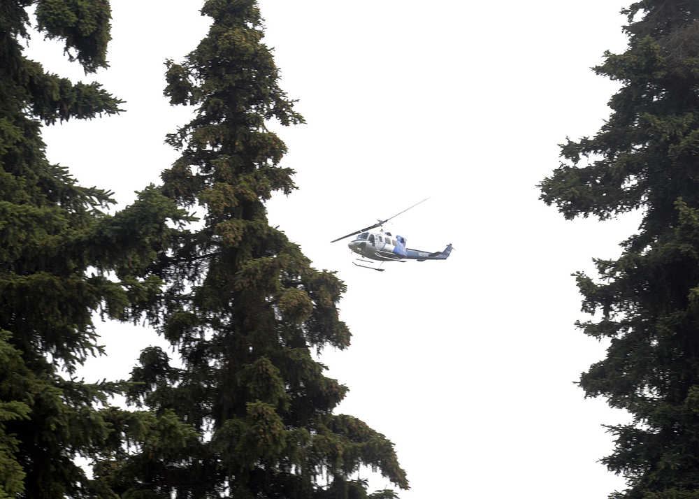 Photo by Rashah McChesney/Peninsula Clarion   A forestry service helicopter circles the neighborhood near Cannery Beach Road where reports were made of a brush fire Tuesday July 22, 2014 in Kenai, Alaska.