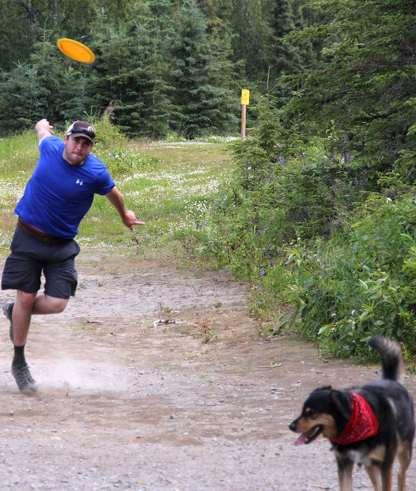 Photo by Dan Balmer/Peninsula Clarion Mike Miles from Anchorage unleashes a shot July 20 at the Kenai Eagle Frisbee Golf Course while his dog Nova enjoys a walk in the park. Miles, who visited the Kenai Peninsula last weekend, plays disc golf at Kincaid Park every week.