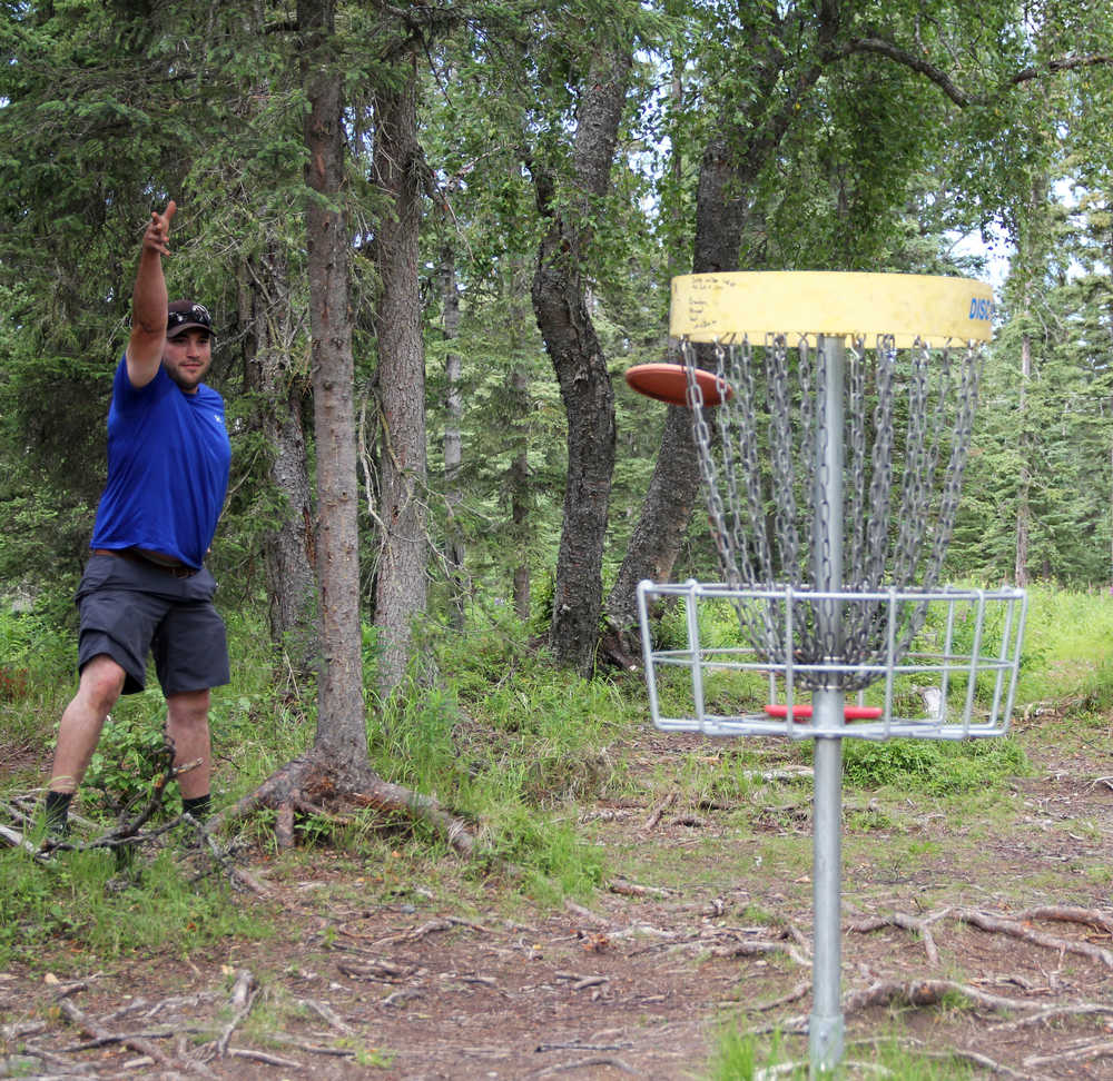 Photo by Dan Balmer/Peninsula Clarion Anchorage resident Mike Miles attempts a birdie shot during a round of disc golf July 20 at the Kenai Eagle Frisbee Golf Course. The shot clanged off the basket and MIles settled for a par.