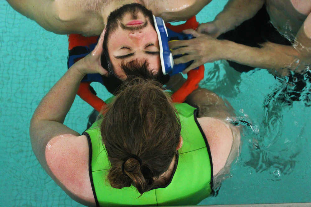 Photo by Kelly Sullivan/ Peninsula Clarion Landon Lightfoot lays patiently as Janet Gaftenby practices strapping him into a water rescue stretcher, June 30, at the Nikiski Pool.