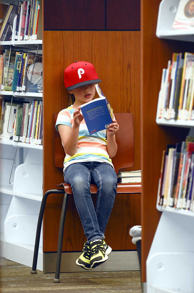 Photo by Rashah McChesney/Peninsula Clarion Sonja Kjostad, 8, of Wasilla digs into a book Monday July 28, 2014 at the Soldotna Public Library in Soldotna, Alaska.