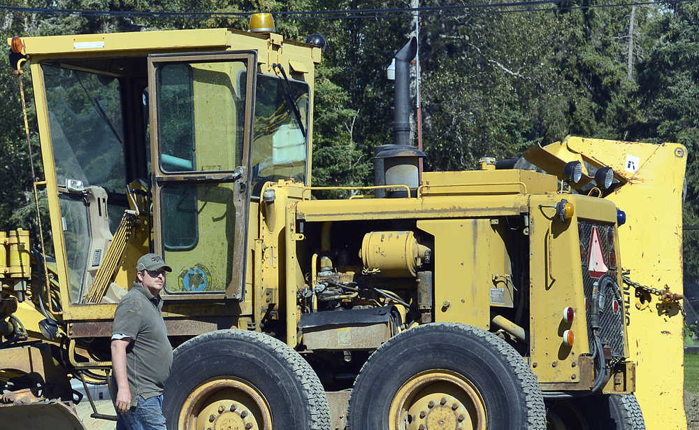 Photo by Rashah McChesney/Peninsula Clarion  Aron Endries, of Endries Construction, guides a motor grader in front of an overturned crane on Beaver Loop Road Wednesday July 30, 2014 in Soldotna, Alaska.  The crane overturned as employees were attempting to move segment of an old culvert being replaced along the road.