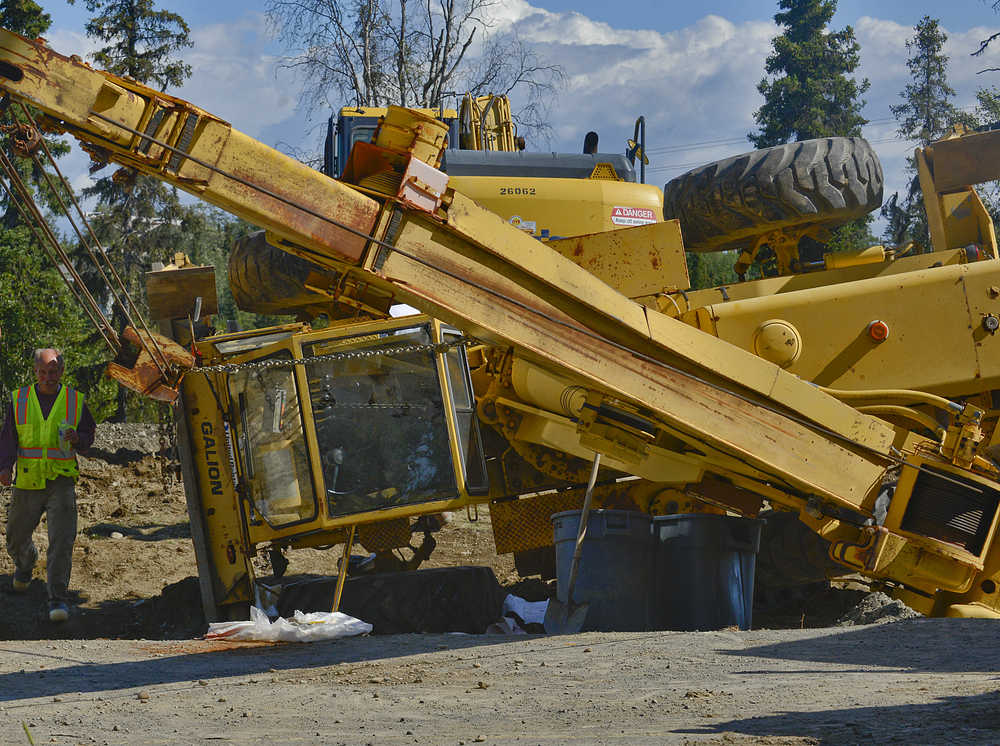 Photo by Rashah McChesney/Peninsula Clarion  Peter Endries walks next to an overturned crane at a jobsite on Beaver Loop Road Wednesday July 30, 2014 in Kenai, Alaska.