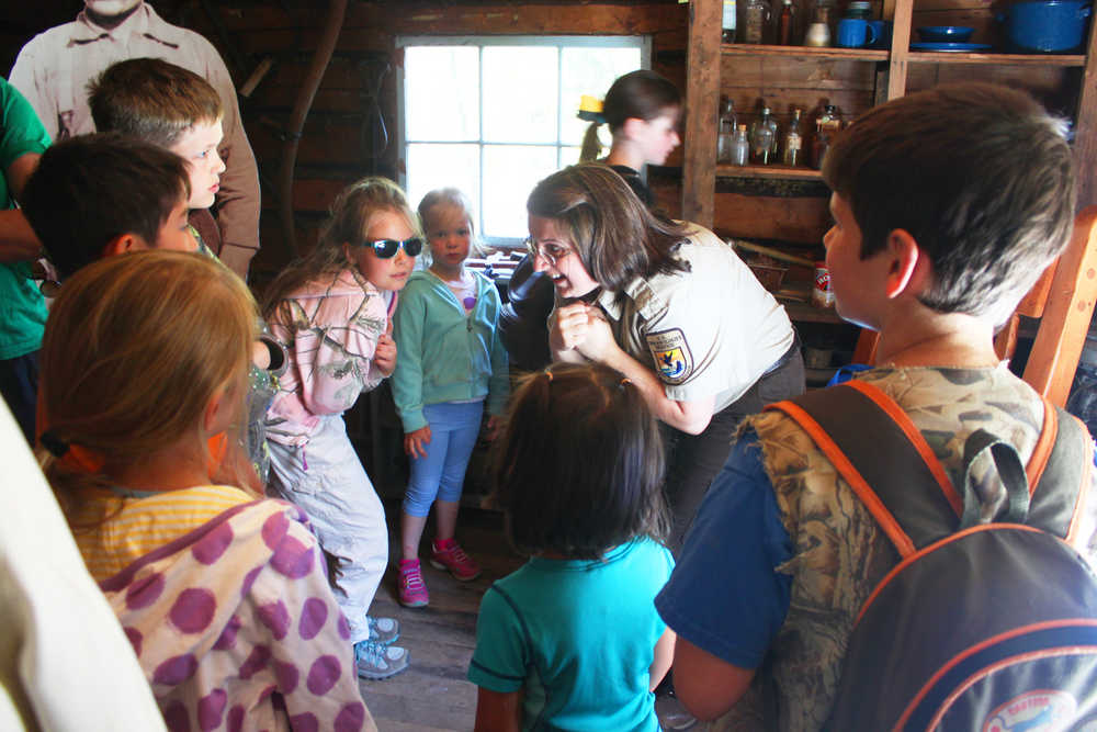 Photo by Kelly Sullivan/ Peninsula Clarion Kenai Wildlife Refuge park ranger Leah Eskelin talks about what it was like to sleep in a log cabin in the middle of winter to her groupd of participants in the Family Explorer Program, Saturday, August 2, 2014, on the Keen-Eye Nature Trail in Soldotna.