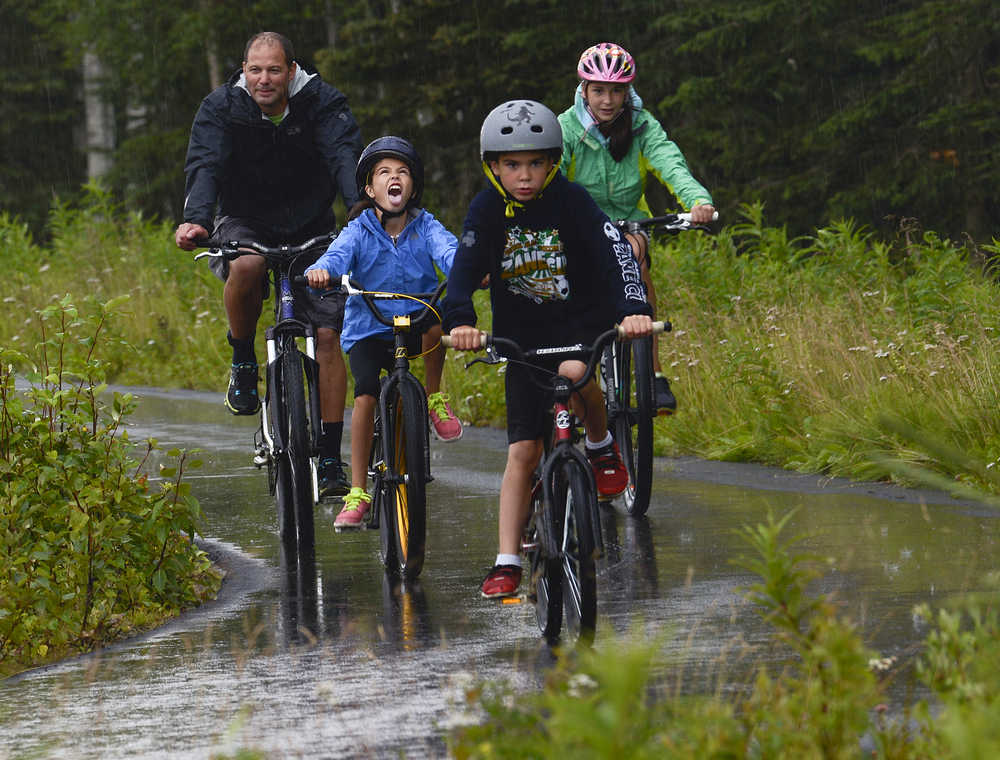 Photo by Rashah McChesney/Peninsula Clarion  (left) Chad Arthur bikes with his kids, Erika Arthur, 11, Andrew Arthur, 8, and Kellie Arthur, 13, during a rainstorm Sunday August 3, 2014 in Kenai, Alaska.  Chad Arthur said the group was headed to Don Jose's restaurant.