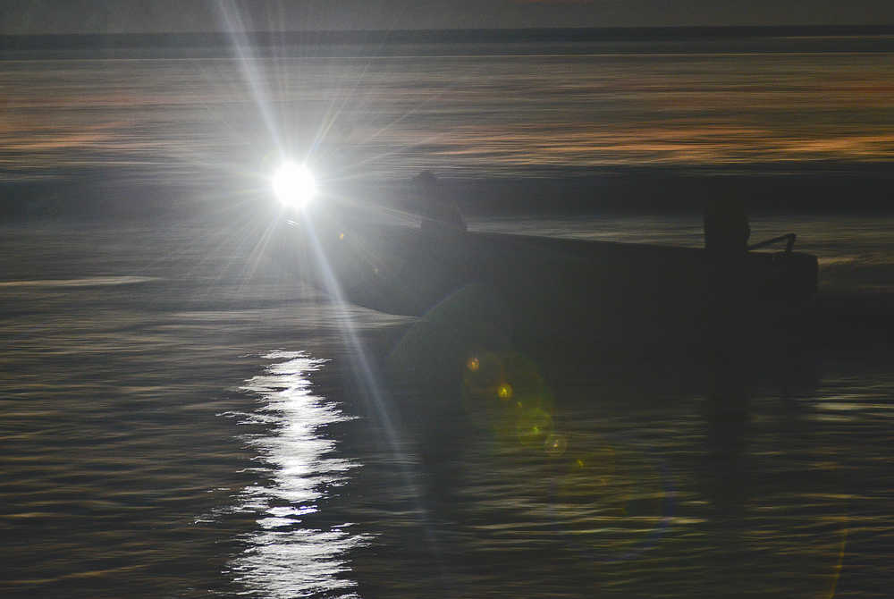 Photo by Rashah McChesney/Peninsula Clarion A commercial set gillnetting skiff runs out of the mouth of the Kasilof River as a crewmember lights the way with a flashlight during an overnight fishing period Thursday July 17, 2014 in Kasilof, Alaska.
