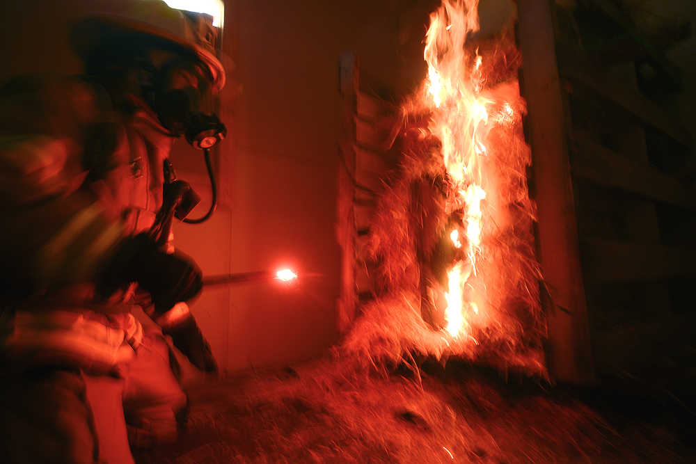 Photo by Rashah McChesney/Peninsula Clarion A firefighter lights a pile of hay with a flare at the beginning of a Central Emergency Services training drill Wednesday August 6, 2014 in Soldotna, Alaska. Crews spent the day in training drills in a new CES facility off of Arc Loop Road.