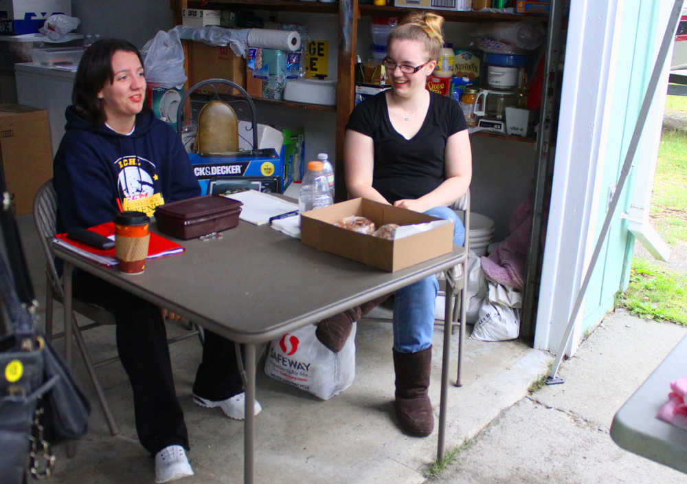Photo by Kelly Sullivan/ Peninsula Clarion Miranda Bicknell, 19, and her younger sister Kelsey, 18, talk in the garage beside the six-family garage sale held at their grandmothers house, Saturday, August 9, 2014, in Soldotna, Alaska.