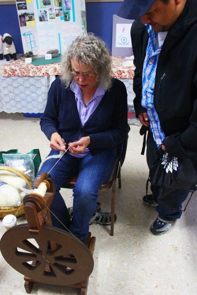 Photo by Kelly Sullivan/ Peninsula Clarion Fireweed Fiber Guild members Lee Choray-Ludden shows Mario Reyna how to spin fibers on a spinning wheel, Friday, August 15, at the Kenai Peninsula Fair in Ninilchik, Alaska.