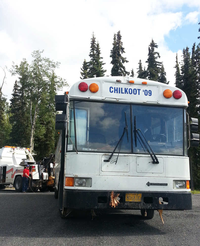 Photo by Dan Balmer/Peninsula Clarion Buddy Linson from Buddy's Garage in Soldotna unhooks his truck from a bus he pulled out of the woods after the bus driver went off the road and crashed into a wooded area off Mile 90 of the Sterling Highway early Sunday morning. The bus driver was pronounced dead on the scene, from natural causes. Seven Snug Harbor Seafoods employees aboard the bus sustained non-life threatening injuries and taken to Central Peninsula Hospital.