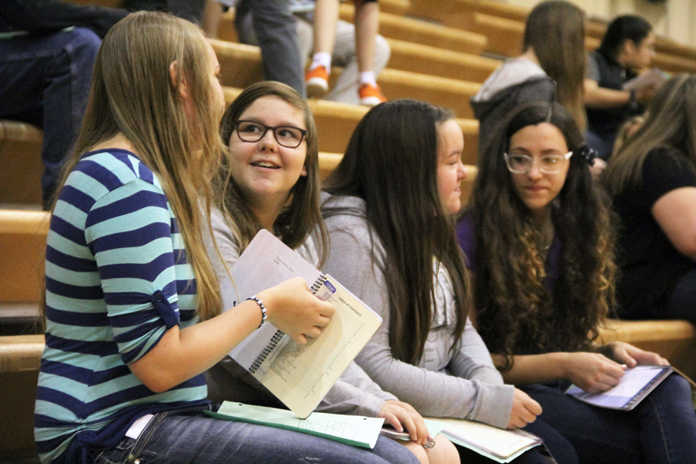 Photo by Kaylee Osowski/Peninsula Clarion From left freshmen Alisa Posey-Schave, Lisa Krol, Kyra Dushkin and Devynn Heath talk and check out their new planners at the freshman class meeting at Kenai Central High School on the first day of the 2014-2015 school year on Tuesday.