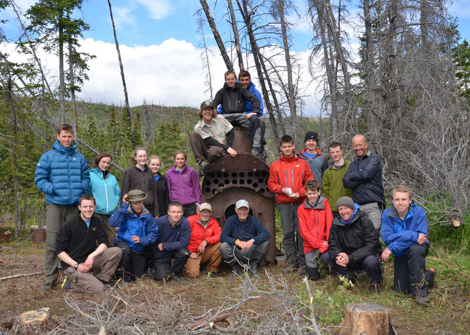 Scottish kids and their chaperones pose in front of a historical 4-ton steam boiler (once used in a lumber mill) that they moved from the shores of Tustumena Lake to higher ground with levers, pulleys and sweat this past summer.  (Photo courtesy Kenai National Wildlife Refuge)