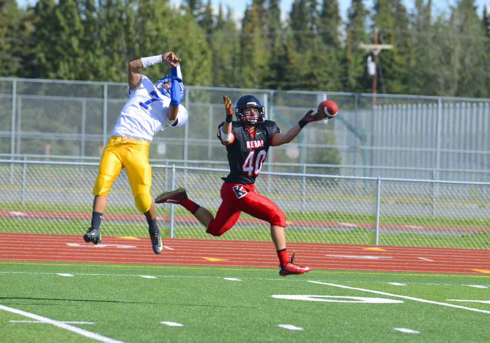Photo by Kelly Sullivan/ Peninsula Clarion Kenai Kardinals Kylee Foree and Kodiak High School's Melvin Javier try to intercept a pass but both miss, Saturday, August 30, 2014 during the varsity game at Kenai Central High School in Kenai, Alaska.