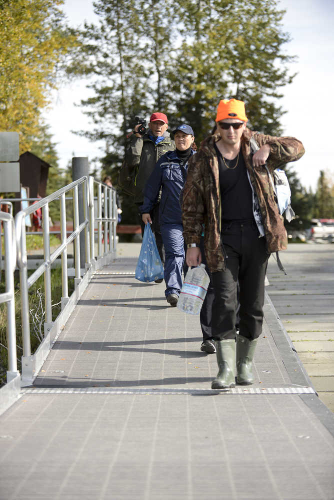 Photo by Rashah McChesney/Peninsula Clarion (left) Viktor Zoloutkhin, of Kamchatka, Margarita Panchenko, of Kamchatka,  and Maksim Ageev, of Sakhalin, head down the dock at The Pillars boat launch September 11, 2014 in Soldotna, Alaska. The group was headed on a guided coho salmon fishing trip with Fishology Alaska.
