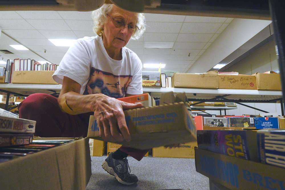 Photo by Rashah McChesney/Peninsula Clarion Barb Christian, of Kenai, arranges a box of books while setting up for the Friends of the Kenai Library book sale at The Home Gallery in the Old Carrs Mall Wednesday  September 17, 2014 in Kenai, Alaska. The sale begins Thursday at noon.