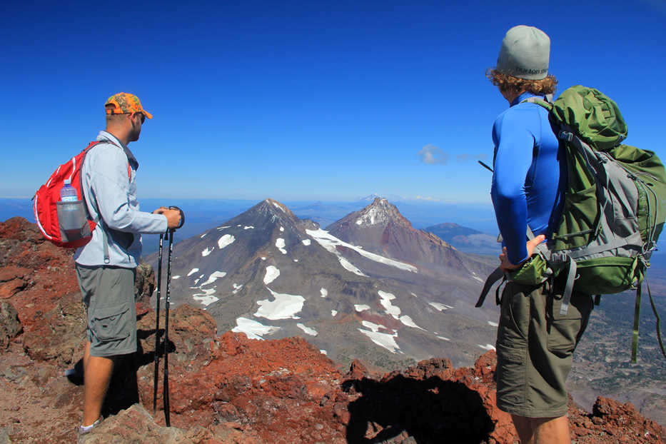 In this September 2013 photo, Ryan Freeman, left, and Andy Gonerka, right, enjoy the view from the summit of South Sister, Oregon's third tallest mountain, which looks out at Middle and North Sister immediately to the north. near Sisters, Ore.(AP Photo/The Statesman Journal, Zach Urness)
