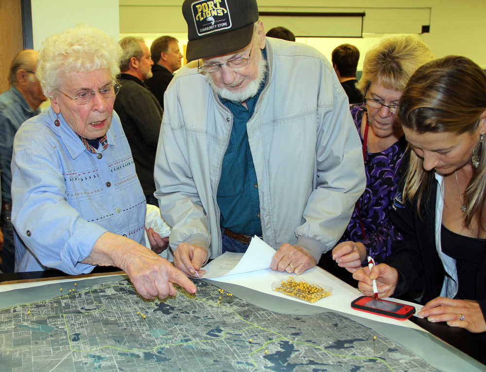 Photo by Dan Balmer/Peninsula Clarion Nikiski residents Jim and Nedra Evenson, victims of a burglary of their property, place a pin on a map that shows how many people in the community have been affected by theft. Hundreds of people attended a town hall meeting Wednesday at the Nikiski Recreation Center.