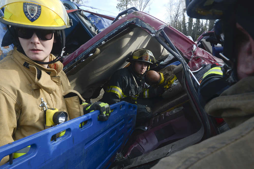 Photo by Rashah McChesney/Peninsula Clarion   (left) Elena Fernandez, a firefighter with the Cordova Volunteer Fire Department races to get her gear on faster than Nikiski Fire Department firefighter Holly Behrens during a skills competition Saturday September 27, 2014 in Kenai, Alaska.