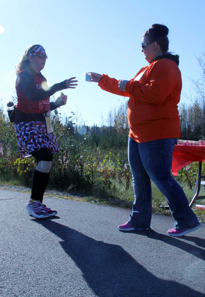 Britney Loveland, a Kenai River Marathon volunteer, offers a drink to half marathon runner Gerri Tokar-Hines, of Wasilla, on Sunday in Kenai. Photo by Kaylee Osowski/Peninsula Clarion