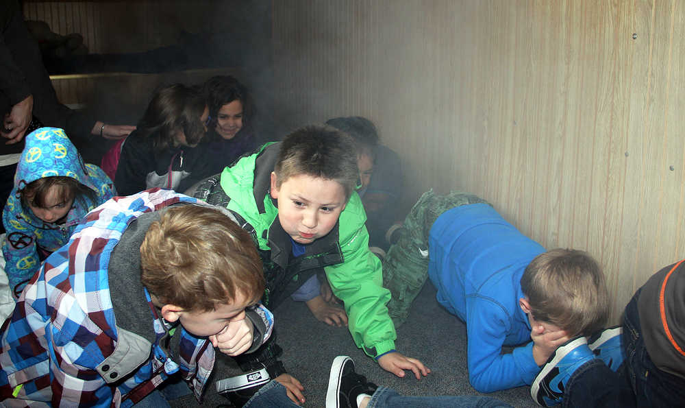 Photo by Dan Balmer/Peninsula Clarion Mountain View Elementary School students from Mandi Vaala's first grade class practice their escape out of a fire safety house Thursday, Oct. 9, 2014 in Kenai. Kenai firefighters are meeting with every class in Kenai in the month of October to educate kids to know how to act in the event of a fire.