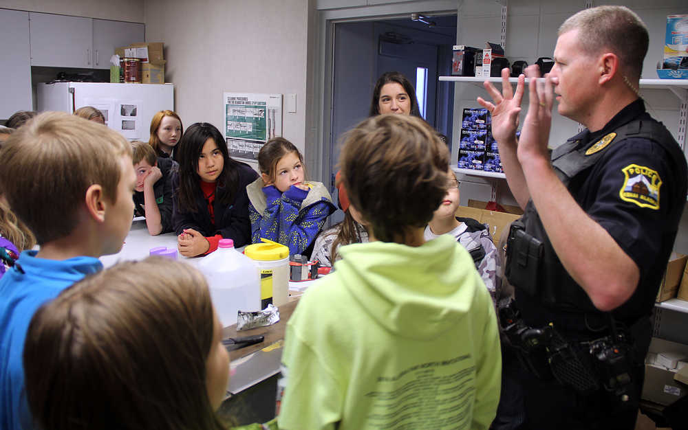 Photo by Dan Balmer/Peninsula Clarion Kenai school resource officer Alex Prins shows Cindy Hurst's fifth grade class from Kaleidoscope School of Arts and Science how police officers take fingerprints during a field trip to the Kenai Police Department Monday, Oct. 6, 2014.