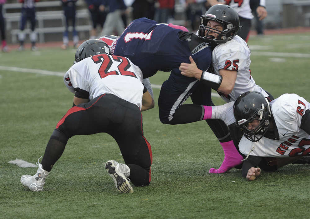 From left, Kenai's Case Gillies, Chase Logan (25) and Kyle Hunter combin for a tackle on North Pole's De' Aundre Campbell.  Photo for the Clarion by Michael Dinneen