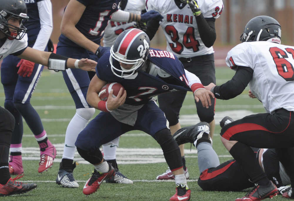 From left, Kenai's Jace Baker (12),and Kyle Hunter (61) team up to stop North Pole's Andrew Rogers.  Photo by Michael Dinneen for the Clarion.