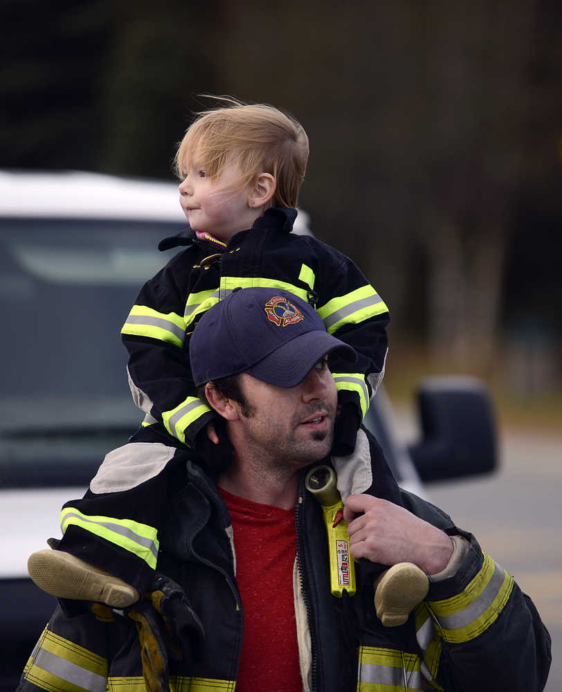 Photo by Rashah McChesney/Peninsula Clarion Kenai Firefighter Abe Porter holds his daughter Eden Porter, 2, as the two collect donations for the Muscular Dystrophy Association during a one-day fill-the-boot campaign Friday October 17, 2014 in Kenai, Alaska.